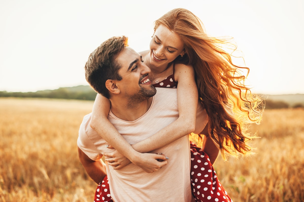 Laughing couple sharing a piggyback ride in a golden field