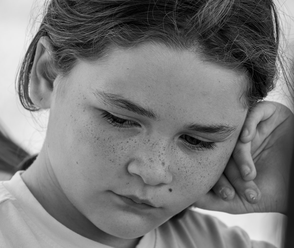 Close-up black-and-white portrait of a thoughtful freckled child